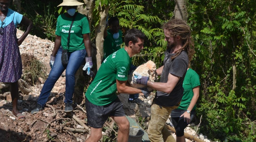 Volunteers on an alternative spring break trip carry rocks and bricks needed to build a playground Alternative spring break trips for college students can include building playgrounds for children